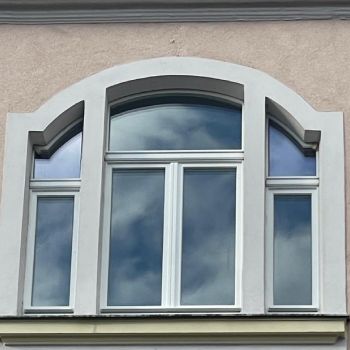 Weiß lackiertes Holzfenster mit Rundbogen und dekorativer Profilleiste